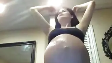 Беременная двойней пышка смазывает огромный живот маслом