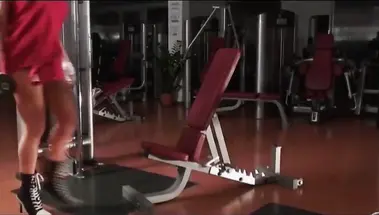 Голая бодибилдерша качает бицепс в спортзале